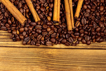 Coffee beans and cinnamon sticks on rustic wooden background. Top view