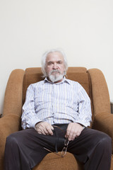 Old sick lonely man in the armchair at home