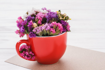 Colorful statice flowers close up. White wooden table background.