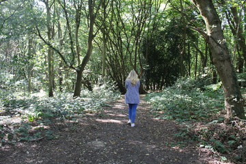 Naklejka na ściany i meble Girl walks through forest path