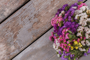 Bouquet of multicolored statice flowers on wood. Copyspace, free space for text.