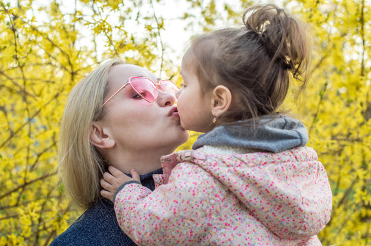 mom in sunglasses kisses her daughter.