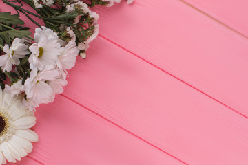 Variety of white flowers on wood and free space for text. Pink wooden background.