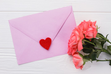 Romantic gift for valentines day. Purple post mail with heart and roses flowers, close up. White wooden background.