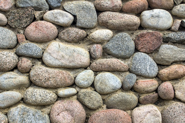 Fototapeta na wymiar natural stone wall of round stone, front and back background blurred with bokeh effect