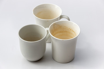 A Close up side view of three dirty white coffee mugs in a group on a isolated white background