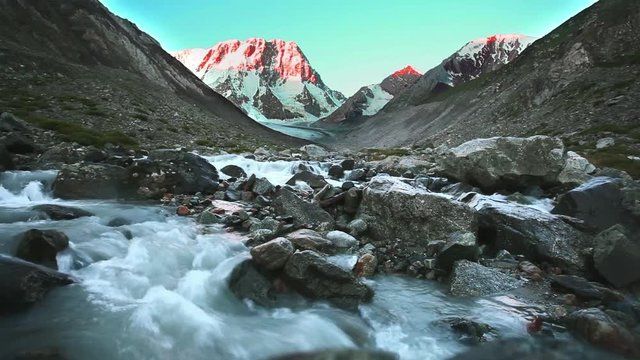 Summit at sunrise and river from glacier. Moraine. Peak Jigit. Tian Shan.
Cinemagraph. Still picture with moving water
