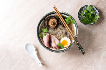 Traditional Japanese Noodle Soup with shiitake mushroom, egg, sliced beef and greens served in...