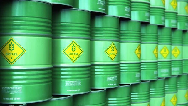 Group of rows of green stacked biofuel drums in storage warehouse
