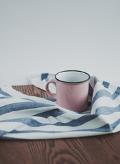 Pink cups and napkin on a wooden table background, close up