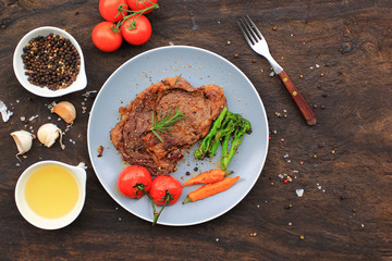 Top view of Beef steaks with rosemary and roast vegetables on dark background, food meat or barbecue