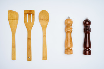 top view of wooden kitchen utensils and spice containers isolated on grey