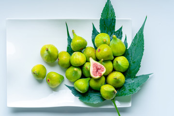 Fruits of fig tree with leaves on white background/ Fresh figs with leaves on rustic table/ Healthy lifestyle concept / Healthy food concept