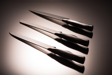 close-up view of various kitchen knives on grey