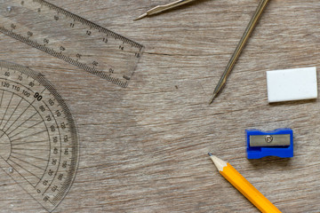 Education or draft tool on wood background (pencil, sharpener, set square, ruler, compass circle)