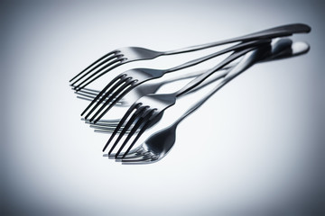 close-up view of set of shiny metal forks on grey