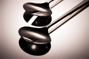 close-up view of shiny stainless steel ladles reflected on grey