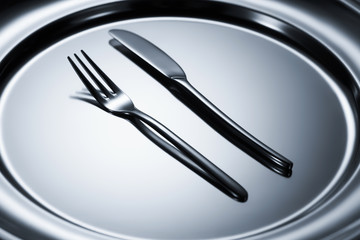 close-up view of fork and knife arranged on shiny metal tray