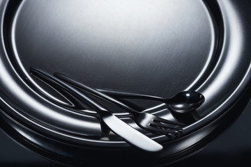 close-up view of cutlery on shiny metal tray on grey