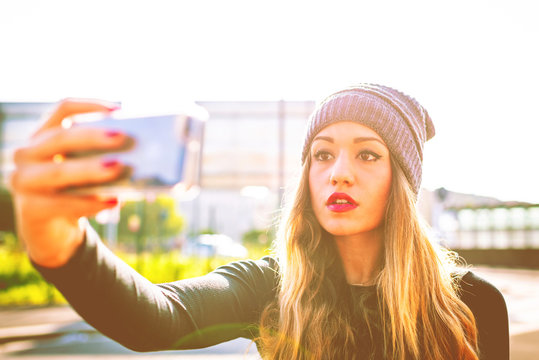 young millennial woman outdoor using smart phone taking selfie - technology, social network, vanity concept