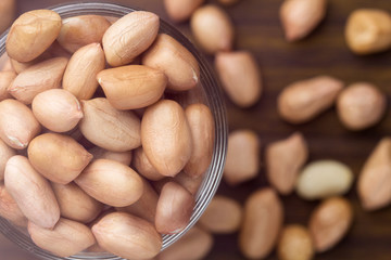 Peanuts in glass cups on wooden close up