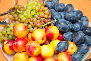 Naklejka na ściany i meble Dish with fruits - plums, peaches, grapes