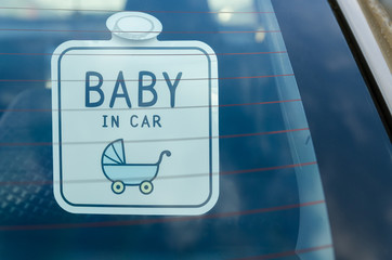 Close up of the baby in car board sign on the car back glass.