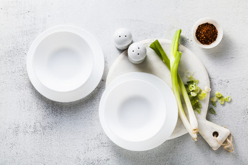 empty plates on the tempty white plates on the table served for soup and green onions. healthy kitchenable served for soup and green onions. healthy kitchen
