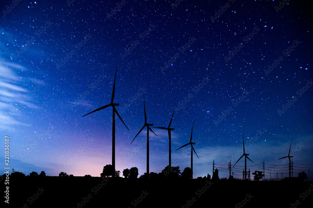 Wall mural eco power. silhouette wind turbines generating electricity with milky way.