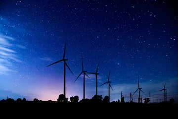 Eco power. silhouette Wind turbines generating electricity with milky way.