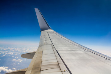 Fototapeta premium wing of an airplane flying above clouds