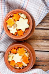 Traditional rustic home vegetable stew in two clay pots on old vintage wooden table.