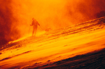 Skier in orange sunset light. Sport photo, silhouette, active life