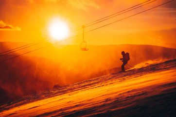 Fototapeta premium Skier in ski resort - orange sport photo, colorful winter sunset light