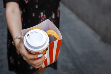 girl holding box with churros (churro) and cup with melt chocolate in the hand.