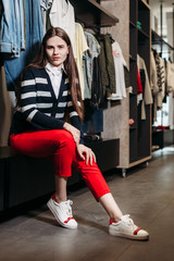 Obraz premium Beautiful model brunette girl posing in clothing store, a new trend of clothes. Banner for a clothing store. For showrooms and fashion stores, cover stories, interior studio
