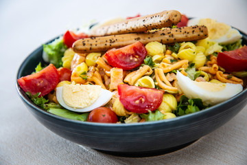 Salad of pasta, egg, smoked salmon tartare, salad and tomato, with a citrus vinaigrette sauce.