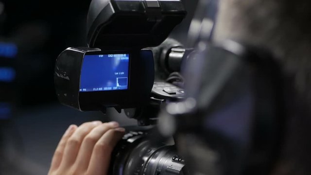 The cameraman is working behind the camera.