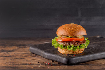 Fresh burger on a wooden background in rustic style.