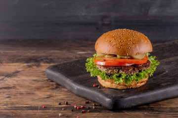 Fresh burger on a wooden background in rustic style.