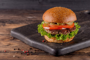 Fresh burger on a wooden background in rustic style.