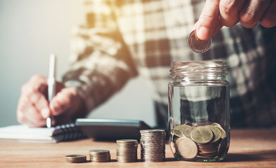 Business man putting coin in glass bottle saving bank and account for his money all in finance accounting concept.
