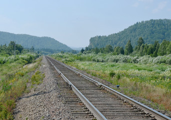 Fototapeta na wymiar Single-track railway on the background of wooded mountains