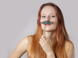 young woman holding a fake moustache on a stick to her face