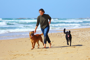 Teenage girl  playing with her dogs on the beach