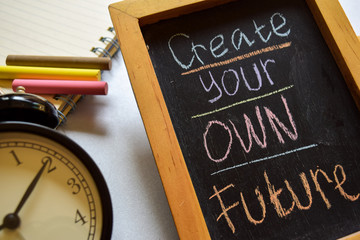 Create your own future on phrase colorful handwritten on chalkboard, alarm clock with motivation...