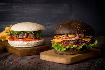 Hamburger with beef and bacon and a white hamburger with french fries on a wooden background.