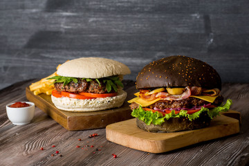 Hamburger with beef and bacon and a white hamburger with french fries on a wooden background.