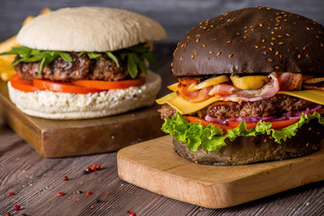 Hamburger with beef and bacon and a white hamburger with french fries on a wooden background.