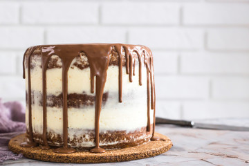 A modern little round naked cake with brown cakes and white curd cream, filled with chocolate. On a...
